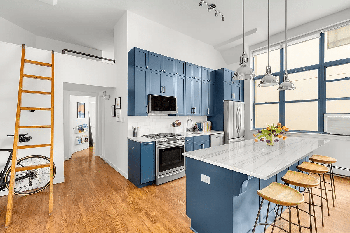 kitchen with bar seating at marble topped island and blue upper and lower cabinets