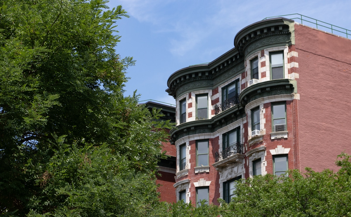 brooklyn - view through the trees of a beaux-arts style brick and limestone early 20th century apartment buidling