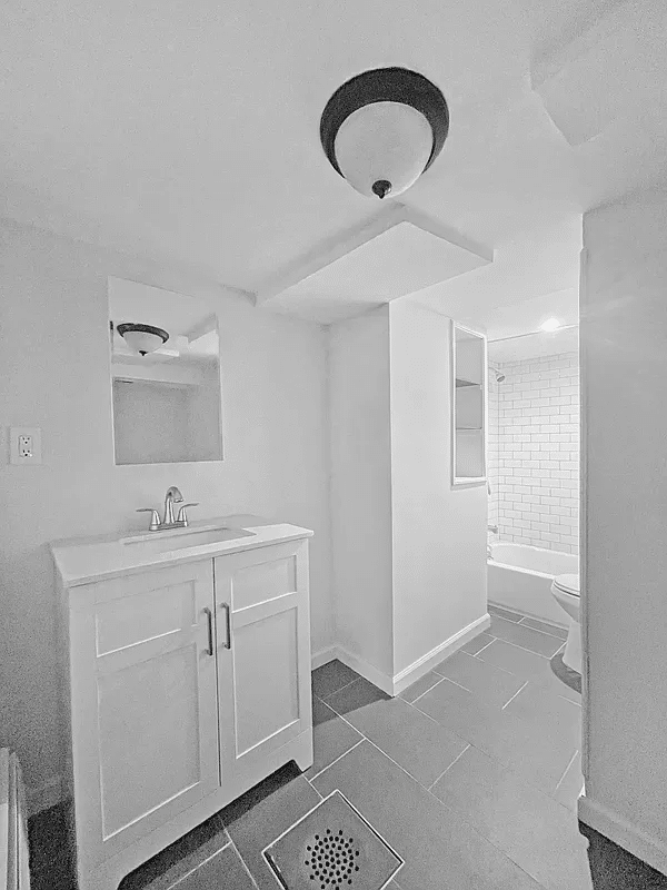 bathroom with white fixtures, large gray floor tile