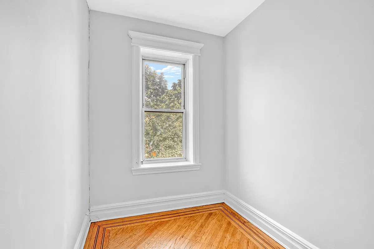 narrow bedroom with one window, wood floor