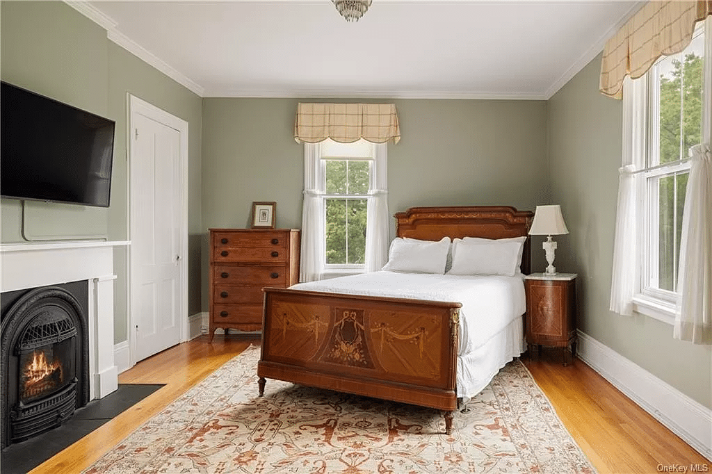 bedroom with mantel, wood floor, two exposures