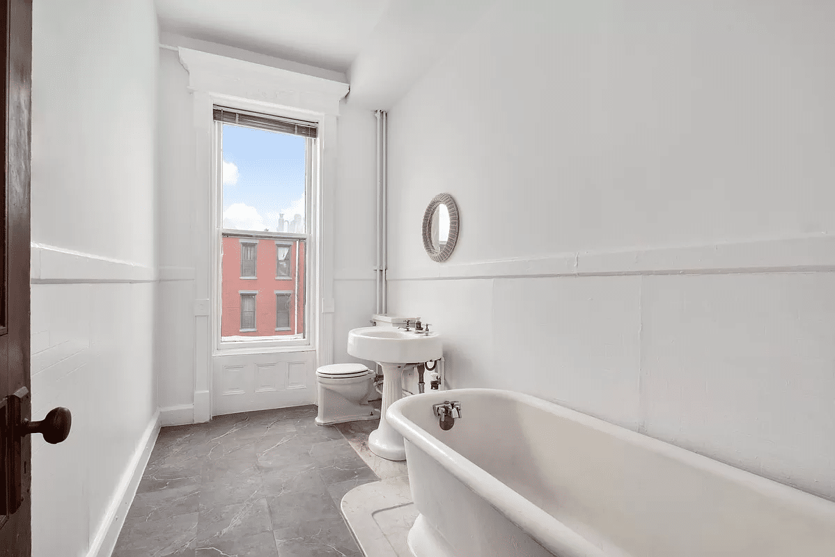 bathroom with white fixtures including pedestal tub