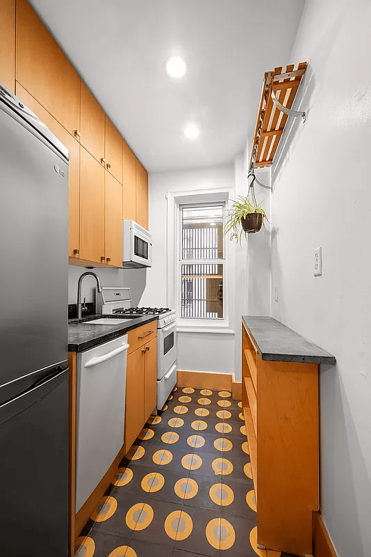 kitchen with graphic yellow, black and gray floor tile, wood cabinets, window