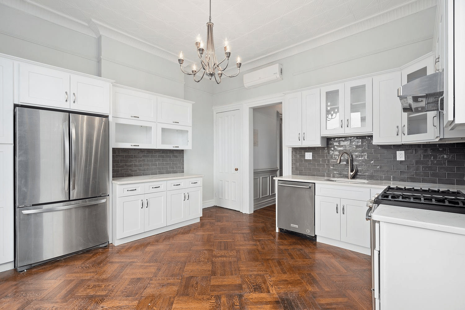 kitchen with wood floor, white cabinets, gray tile
