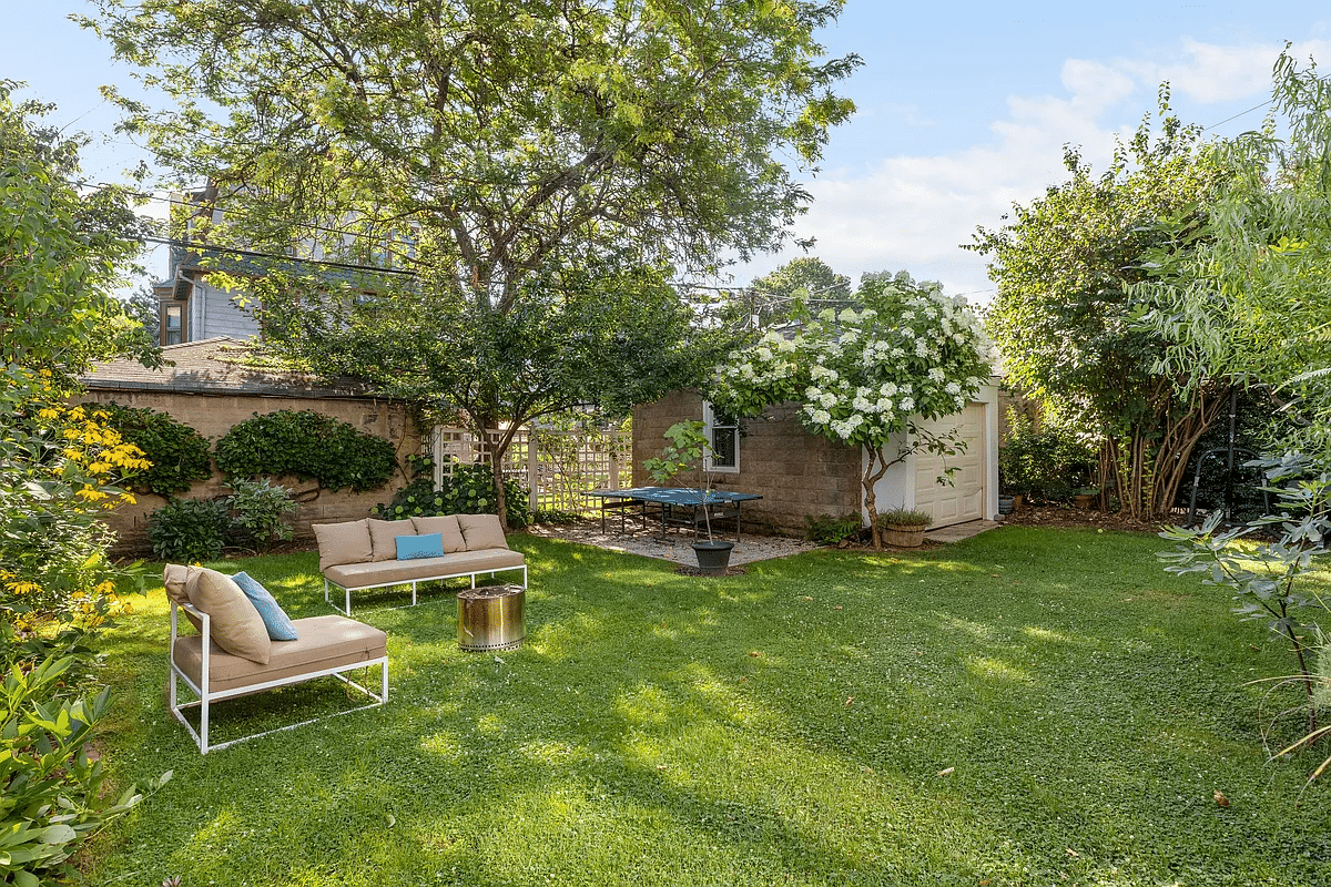 rear yard with a lawn, trees, and a garage