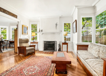 fiske terrace - living room with wood floor, white painted brick fireplace, view into dining room