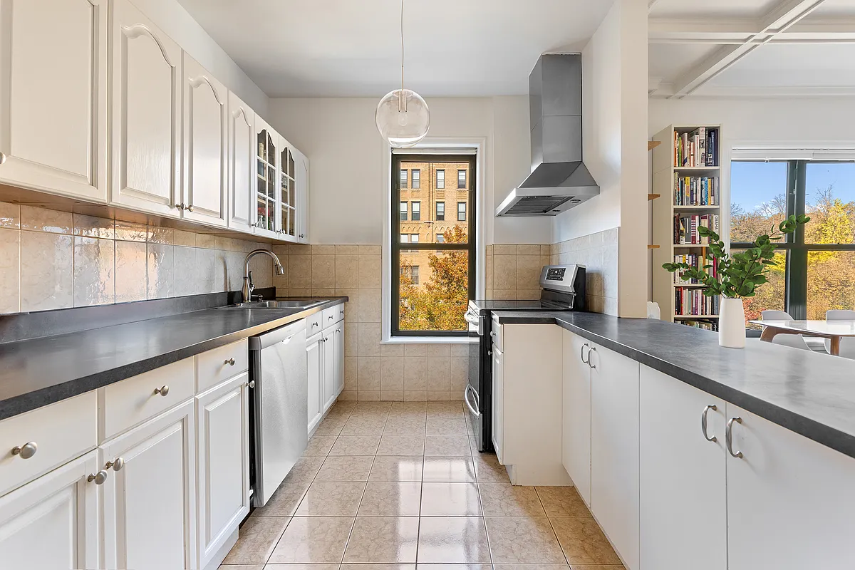 windowed kitchen with beige floor tile and white cabinets