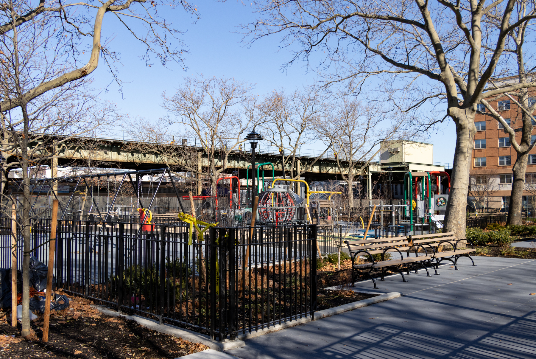 view from Schenck avenue into the park showing new playground equipment, benches, and fencing
