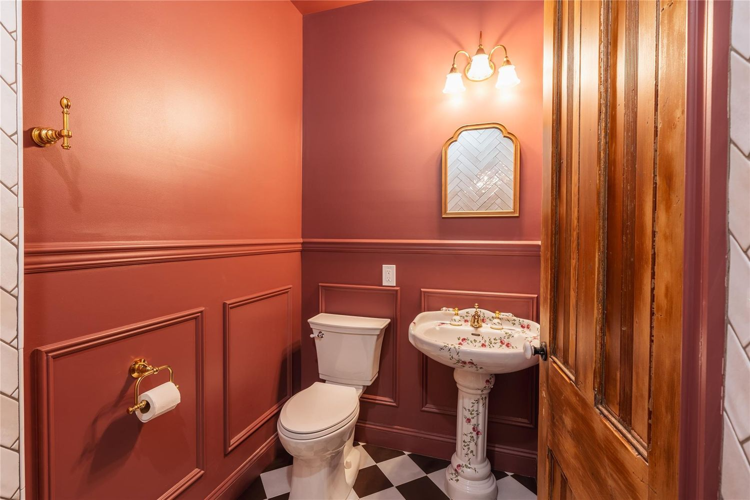 poweder room with terra cotta colored walls and a floral pedestal sink
