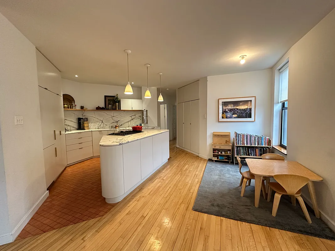 open plan kitchen and dining area with white cabinets and a triangular island
