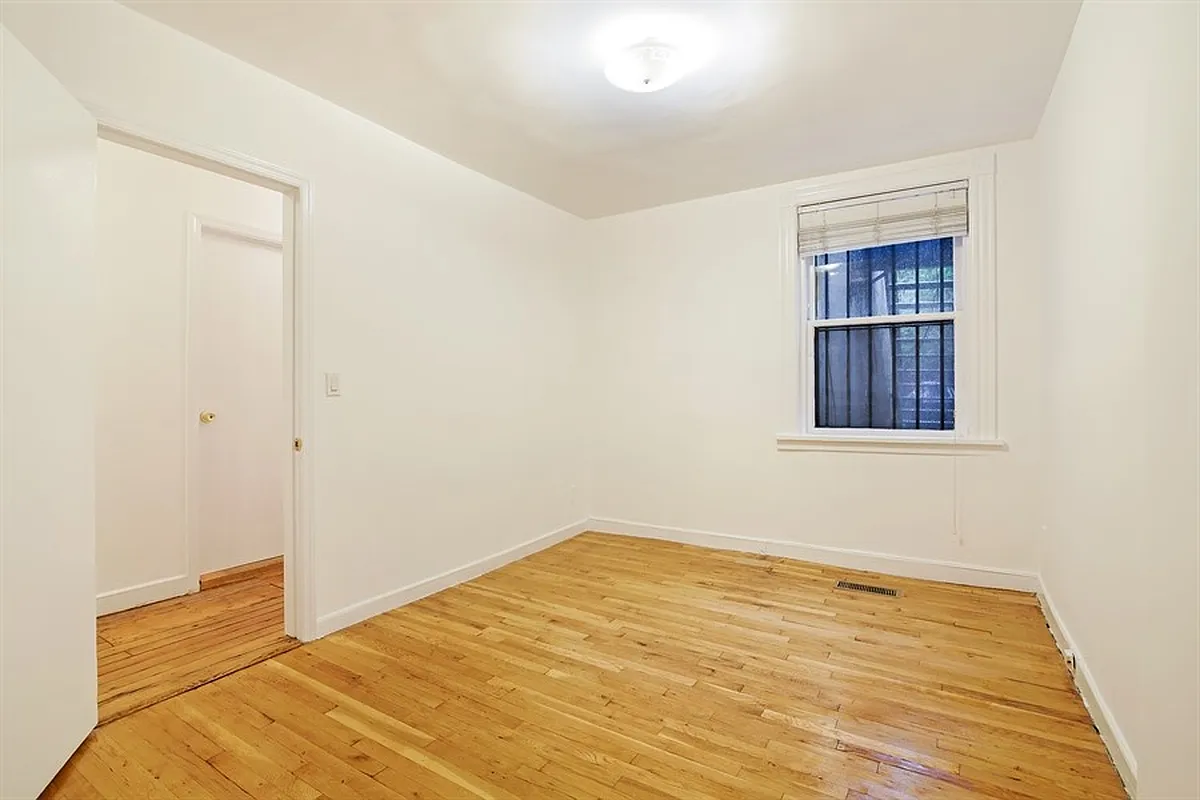 small bedroom with wood floor, white wall
