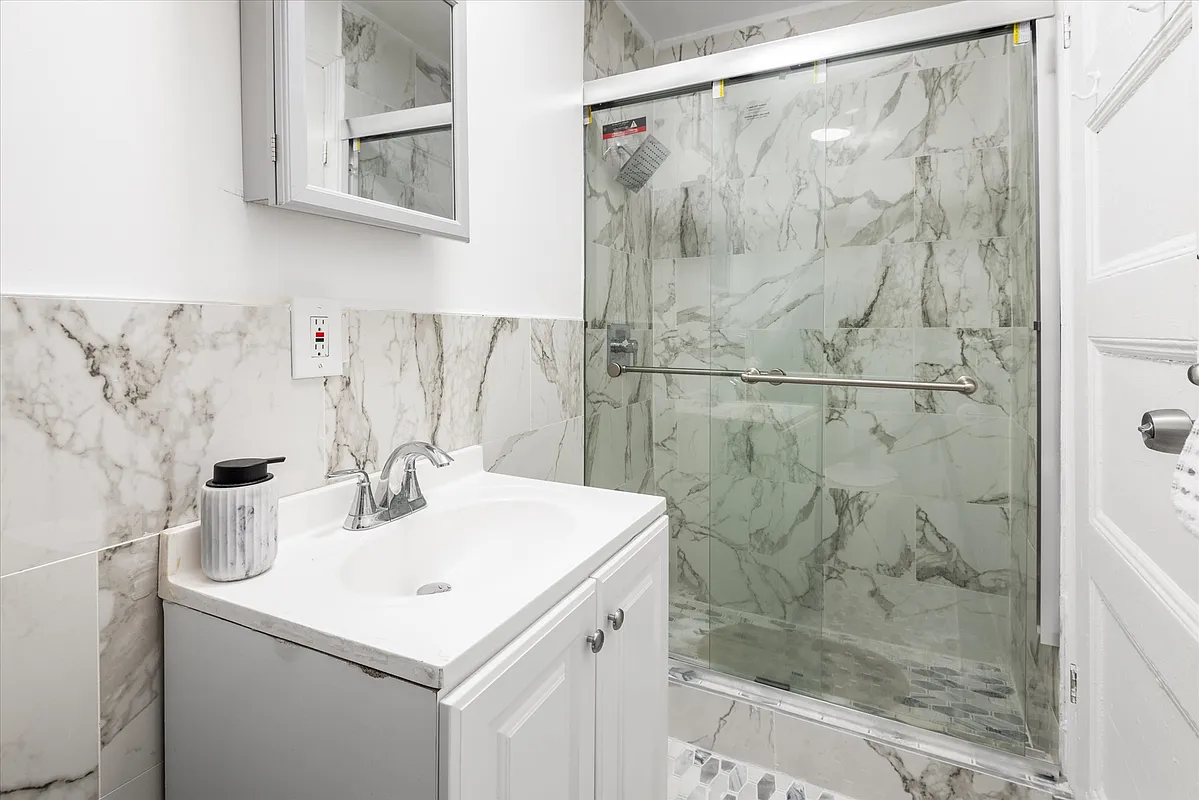 bathroom with marble tile and a shower