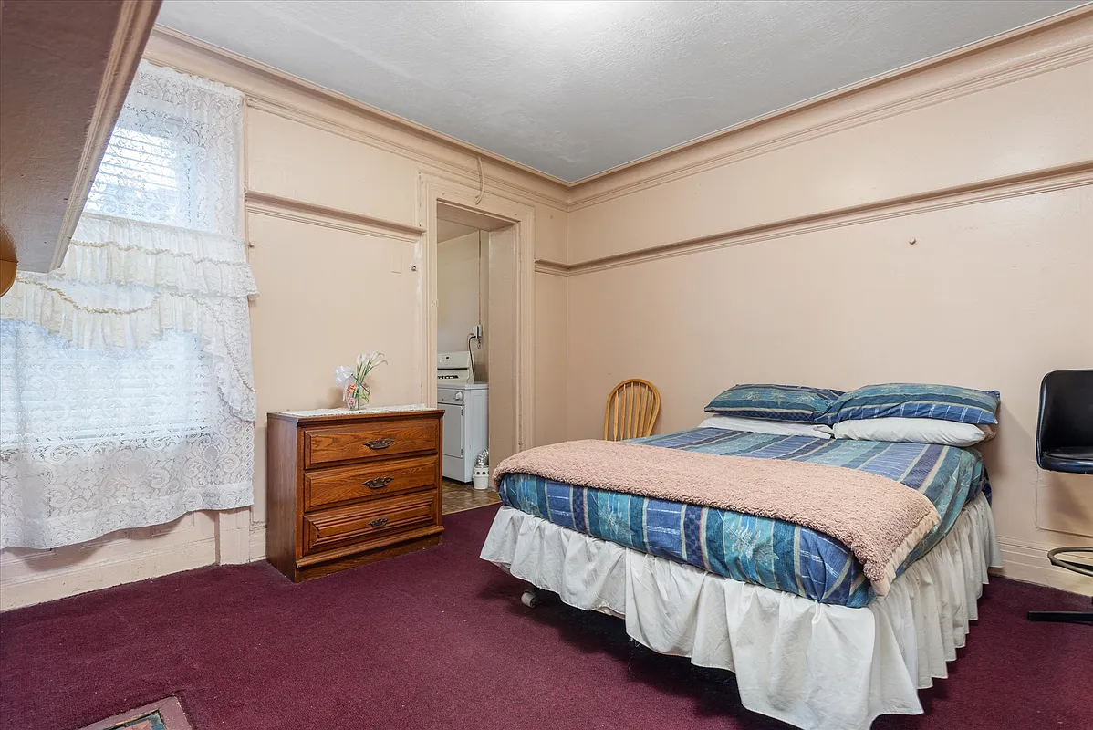 bedroom with moldings, wall to wall carpet and view into kitchen