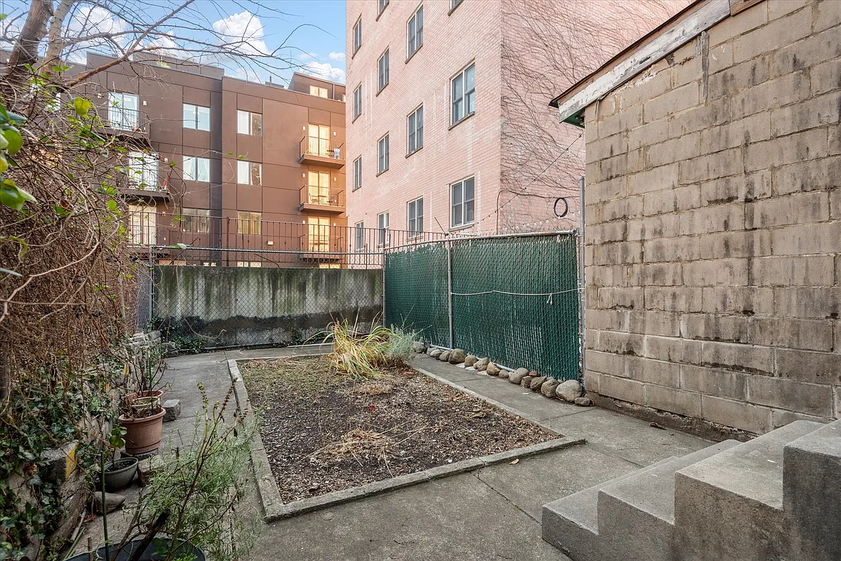 paved rear yard with a center rectangle of soil for planting