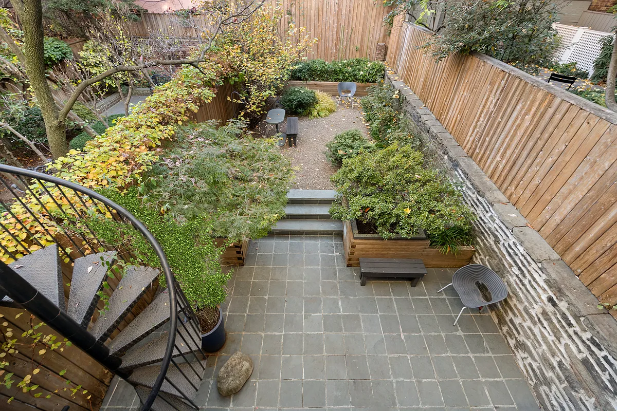 aerial view of rear yard showing paved patio and steps up to gravel yard area with plantings
