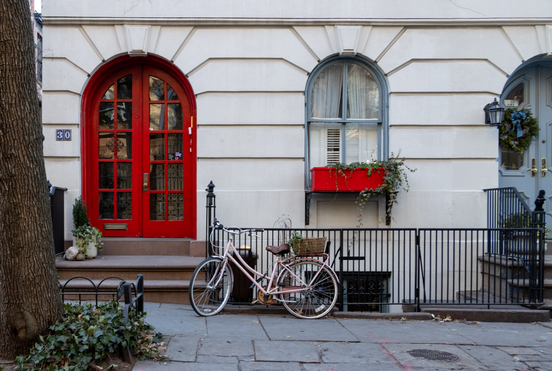 brooklyn - a pink bike leans against a fence near the stoop of a Brooklyn Heights row house with a red door