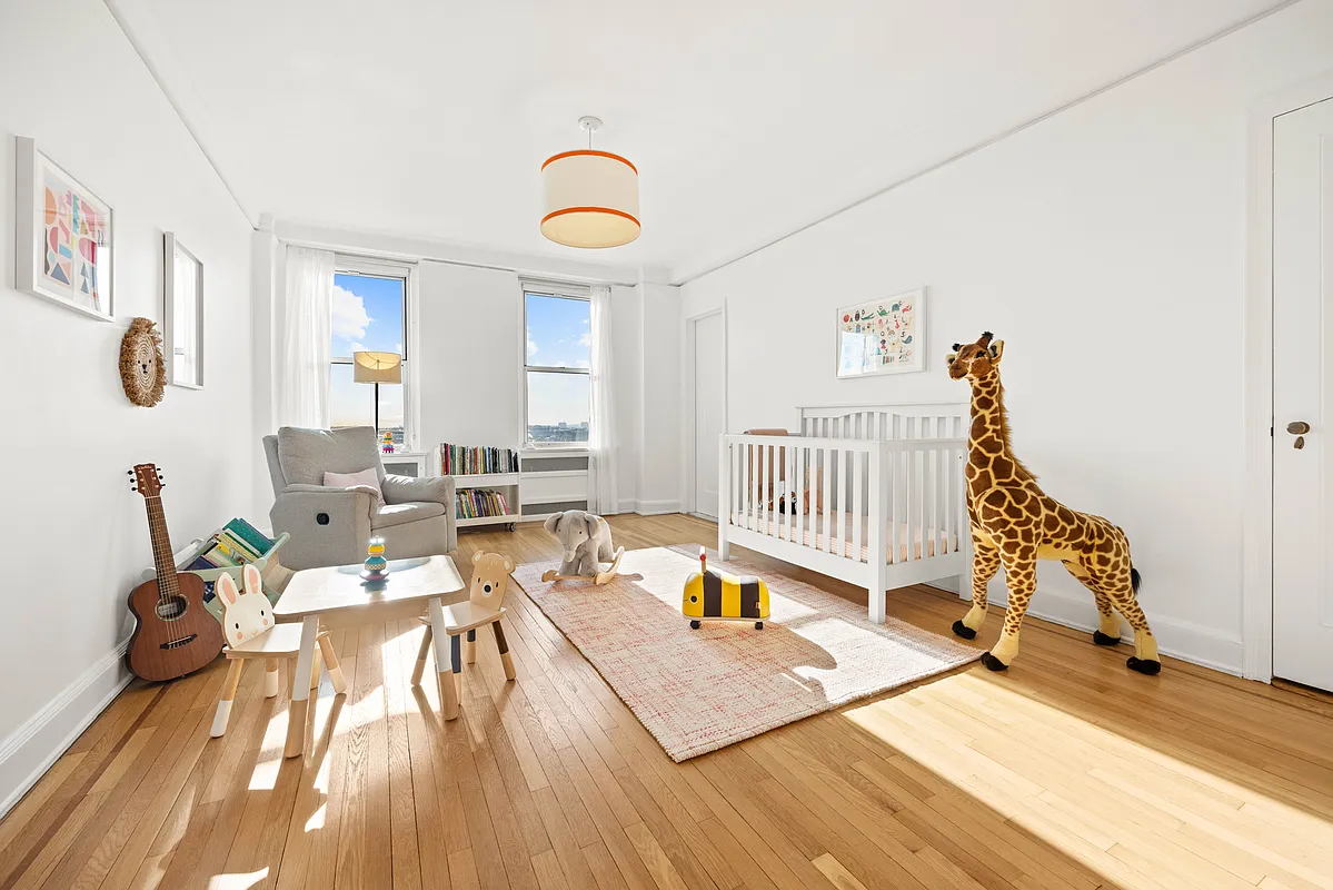 bedroom with wood floor and white walls staged as a nursery