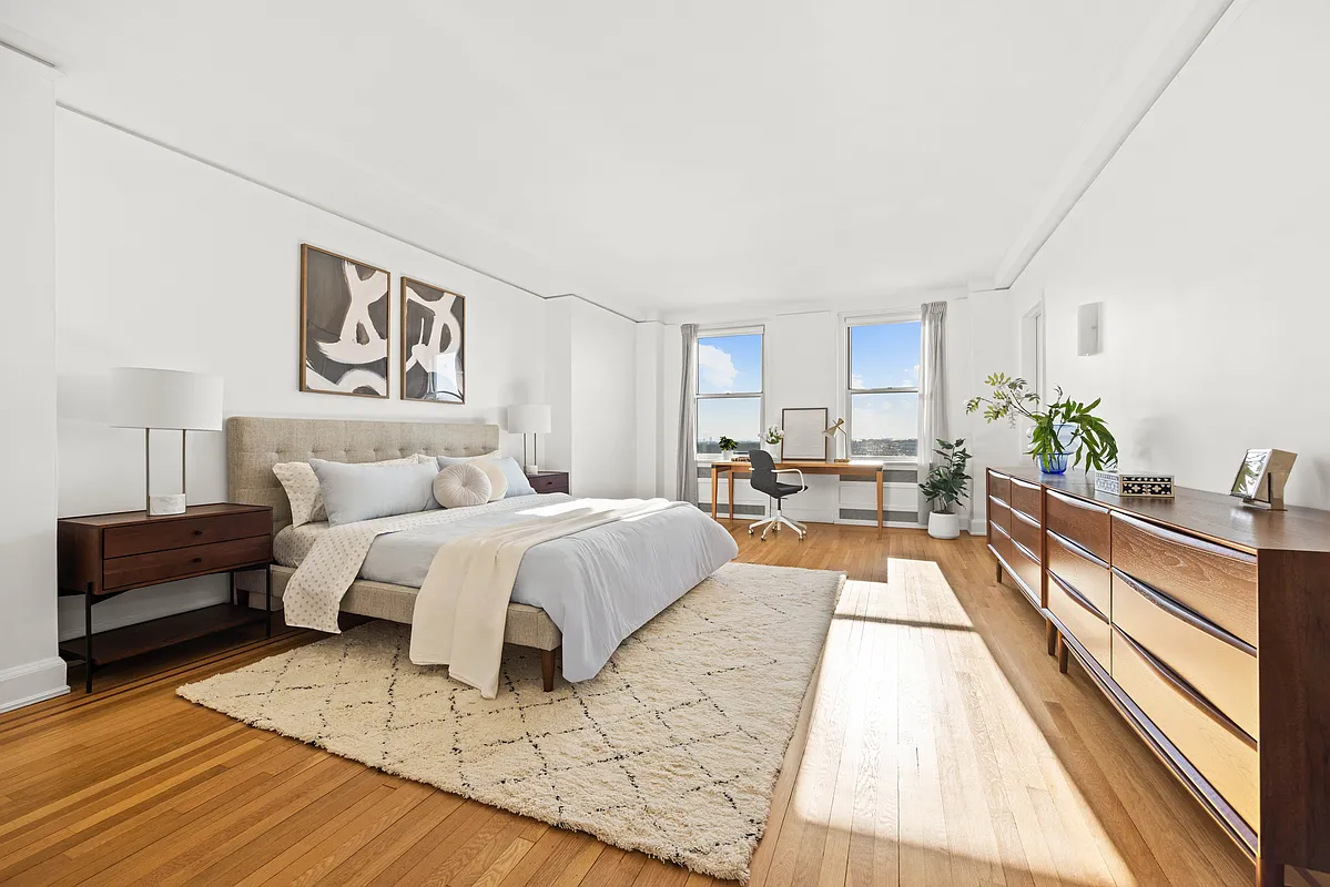 large bedroom with wood floor, white walls and windows with a view