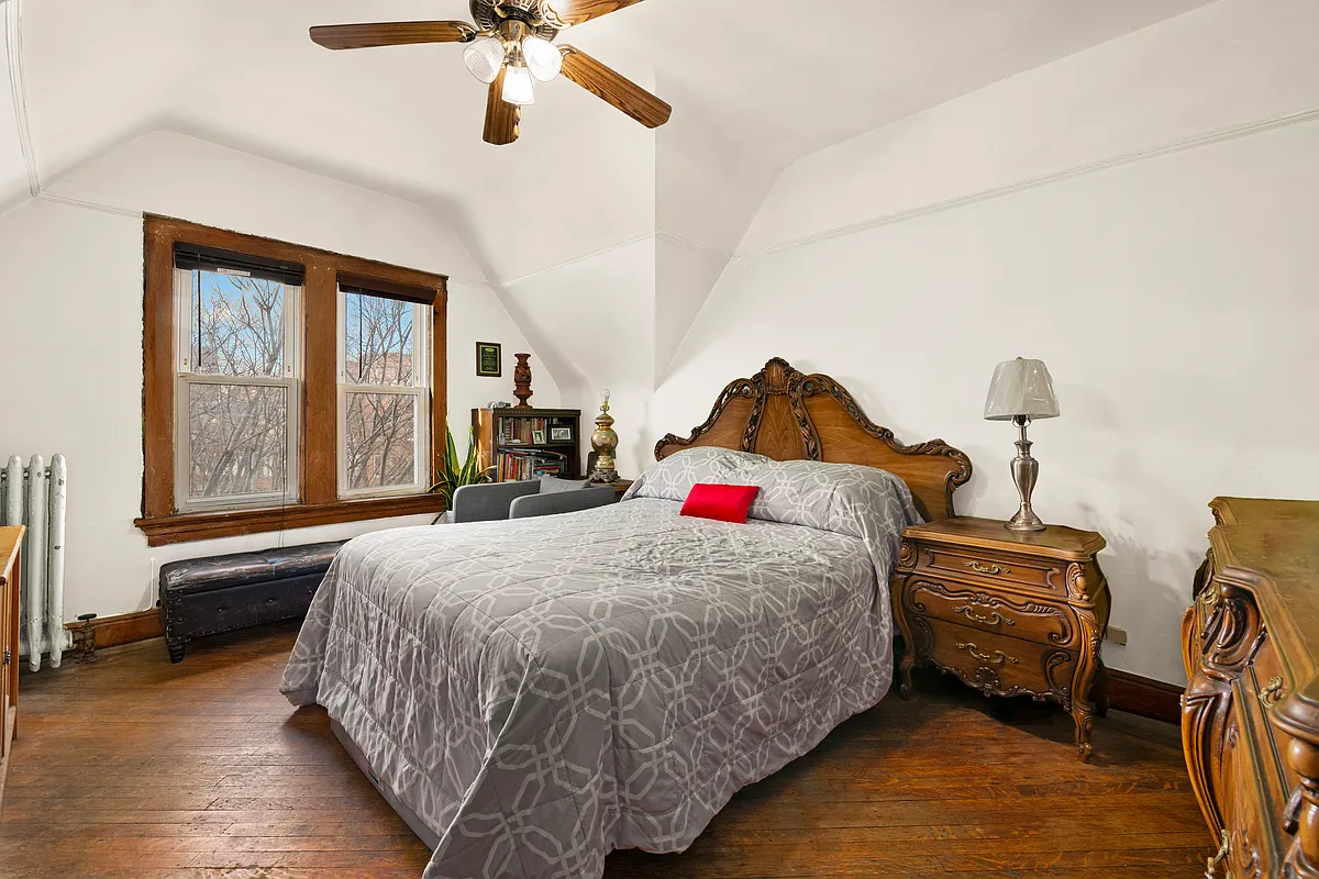 bedroom with angled ceiling, wood floor, ceiling fan