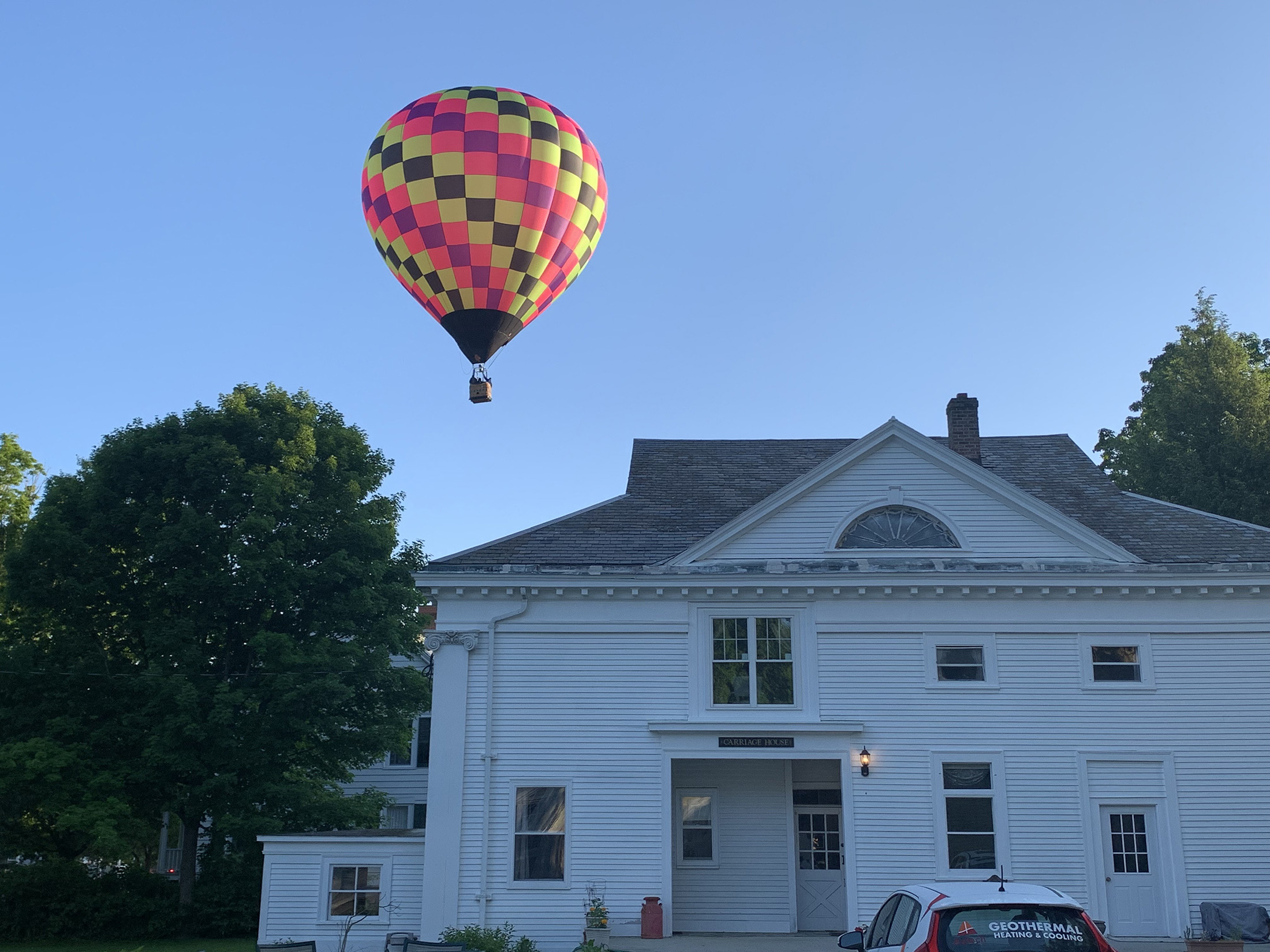 hot air balloon flying over the wood frame carriage house