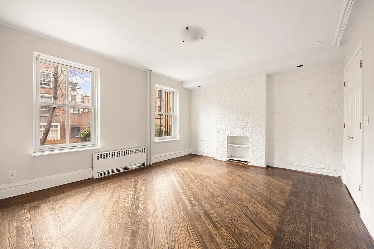 room with wood floor, brick fireplace wall painted white