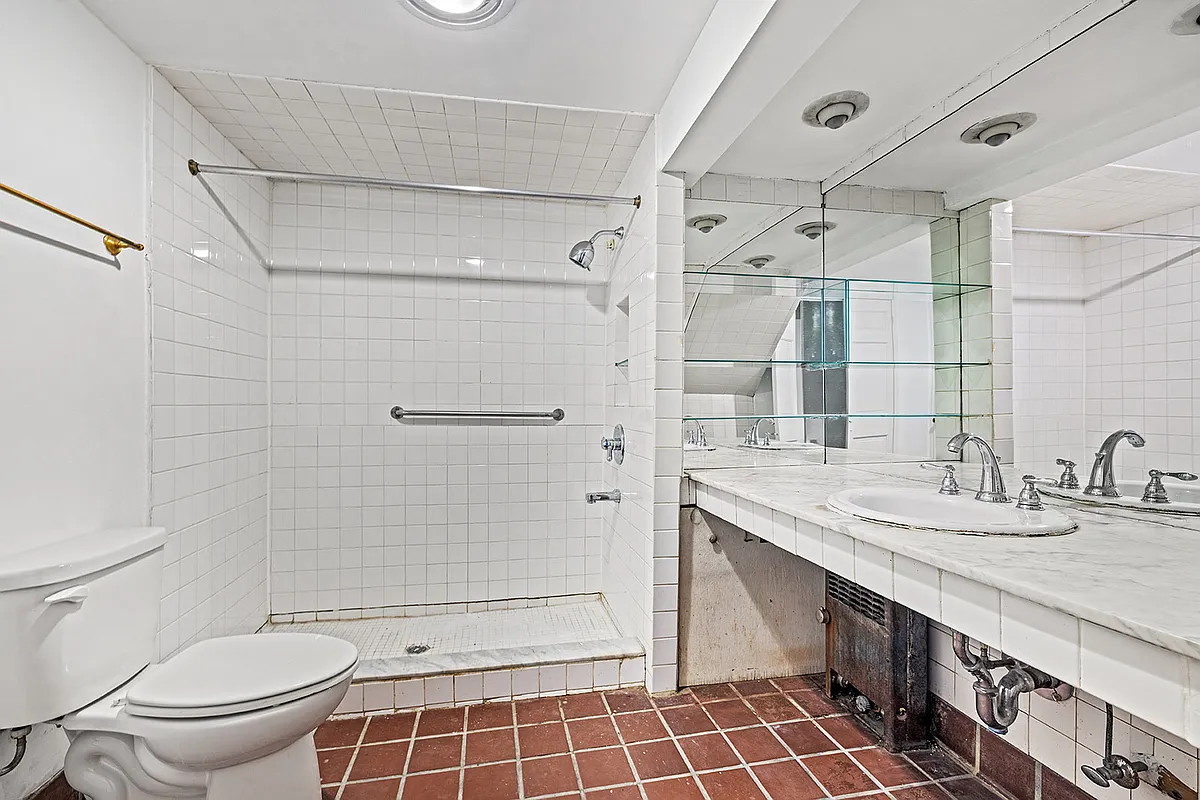 bathroom with terra cotta tile floor, white fixtures and a shower