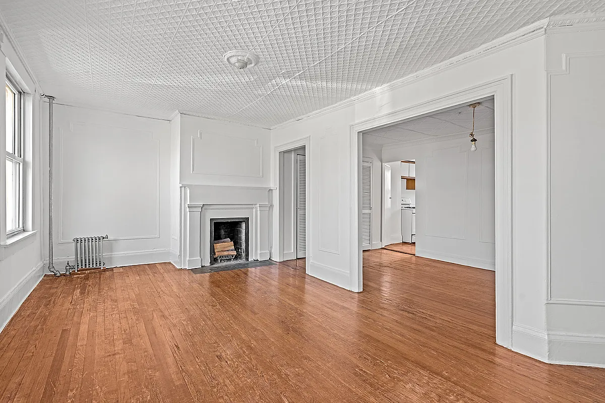 upper unit room with greek revival mantel, tin ceiling, white walls
