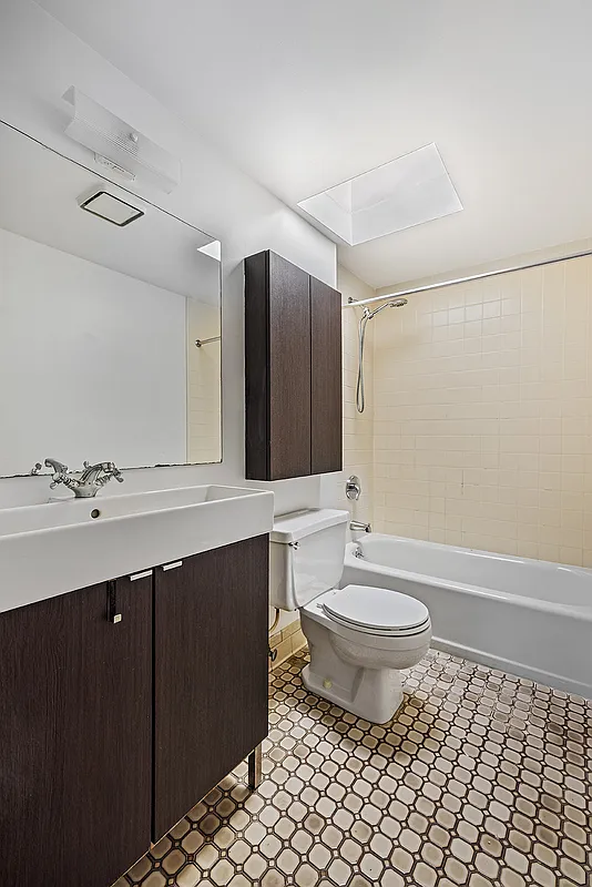 bathroom with white fixtures and a skylight