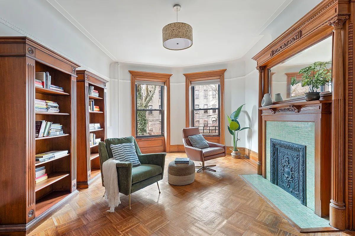bedroom with mantel, wood floor, moldings, set up as a library