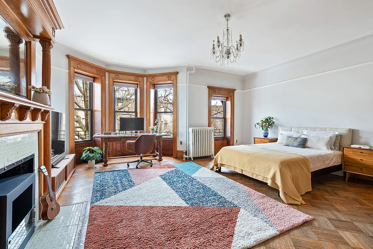 bedroom with wood floor, mantel, picture rail