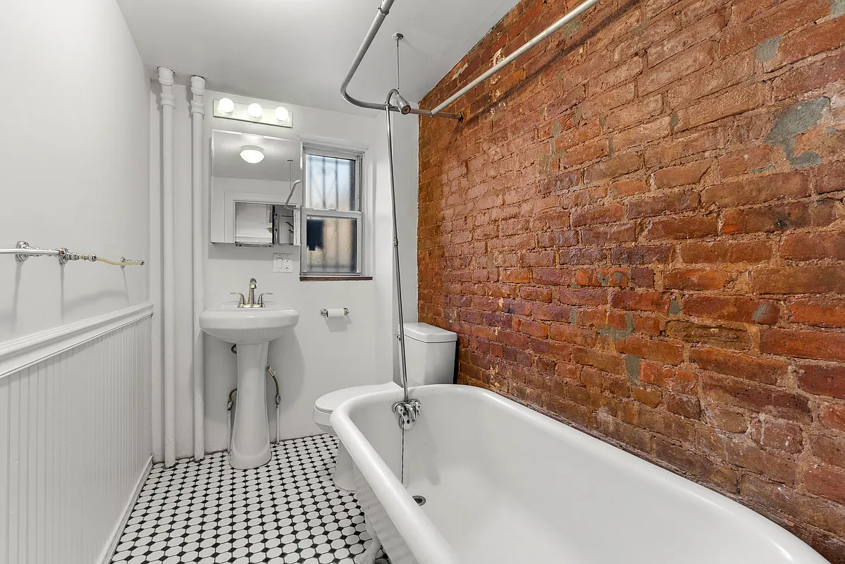 bathroom with exposed brick wall, claw foot tub