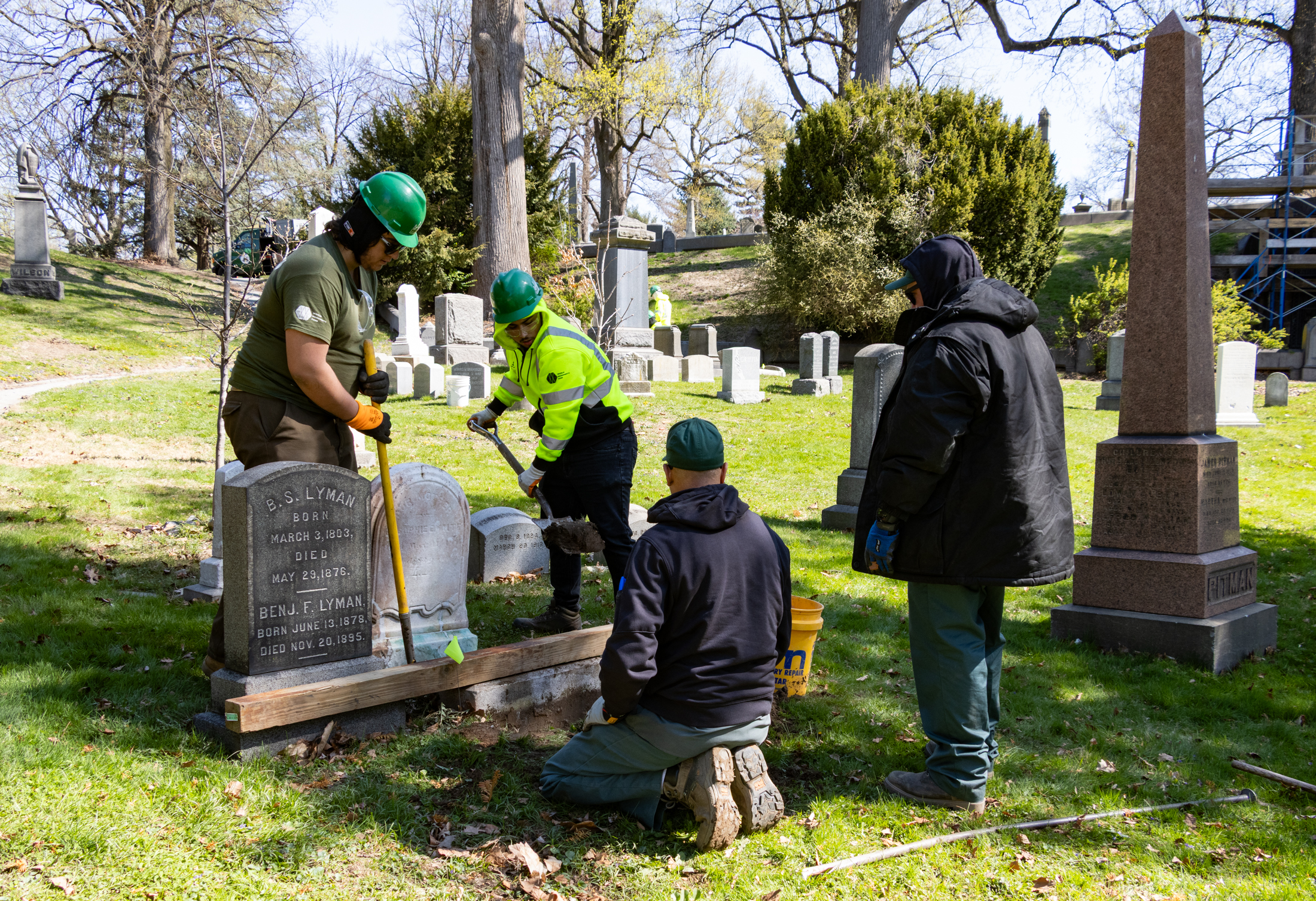 Students work to reset a gravestone that had sunk below grade