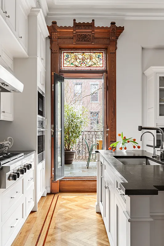 kitchen with white cabinets and a center island and doors to deck along with original moldings and stained glass