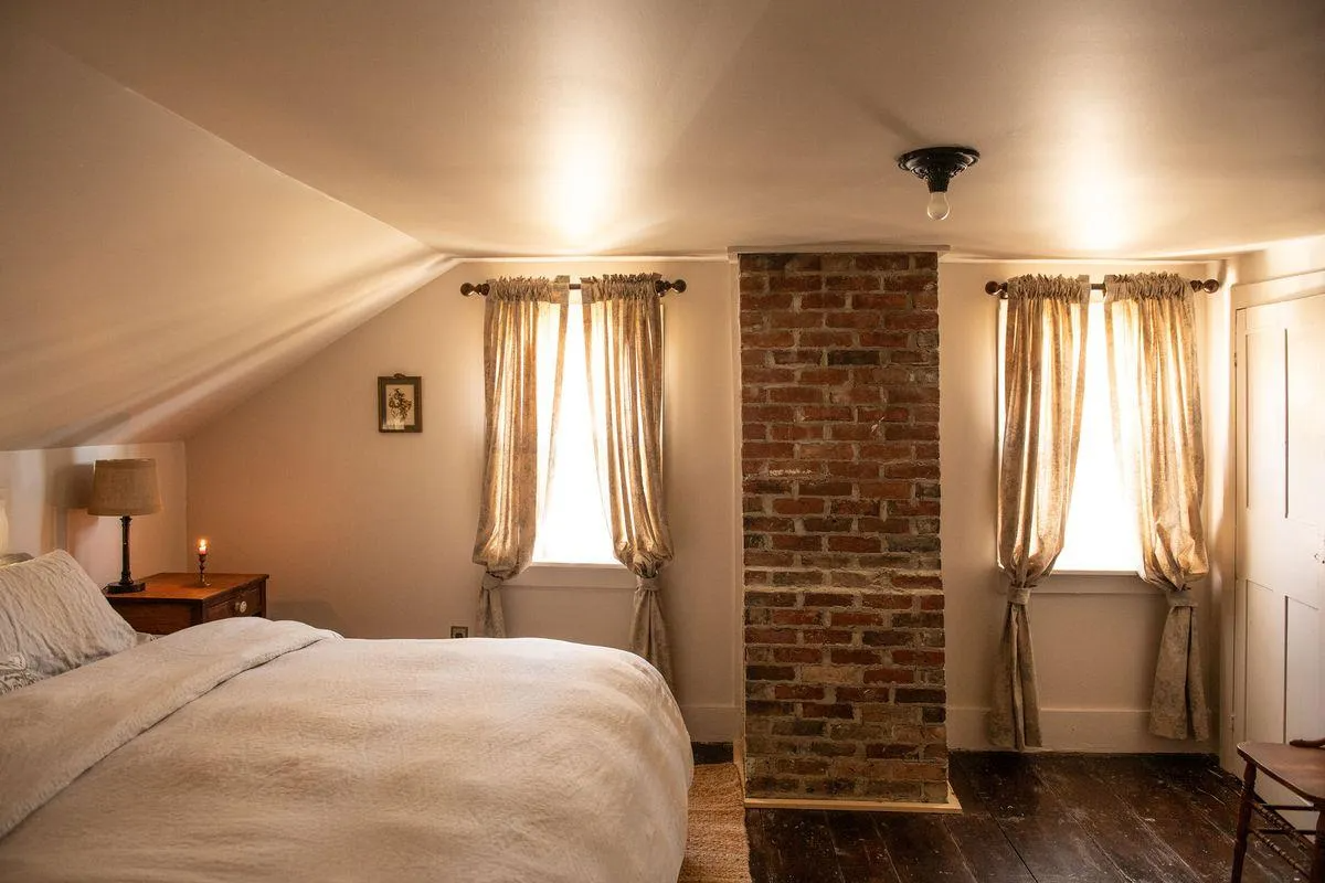 bedroom with two windows, exposed brick chimney wall