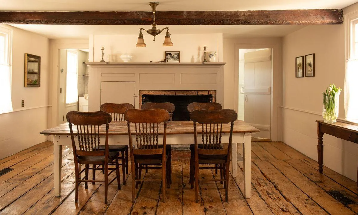 dining room with exposed beam, fireplace, wide planked floorboards