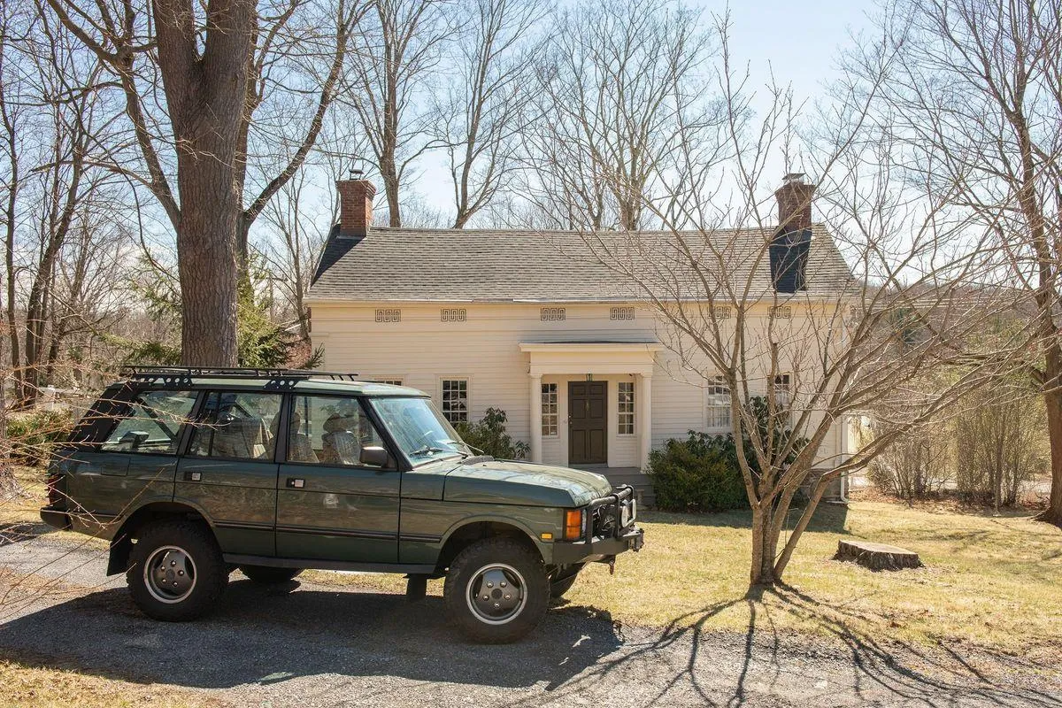 a vehicle parked in front of the greek revival house