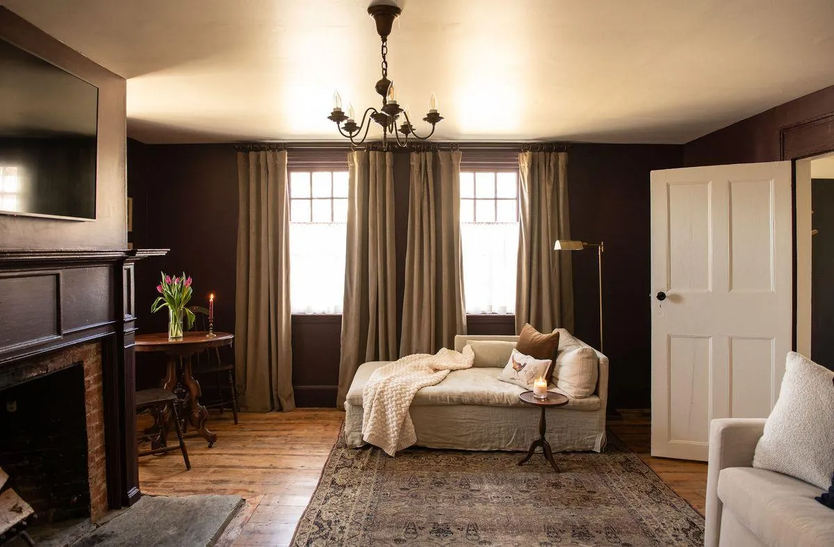 living room with dark walls, mantel, wood floor