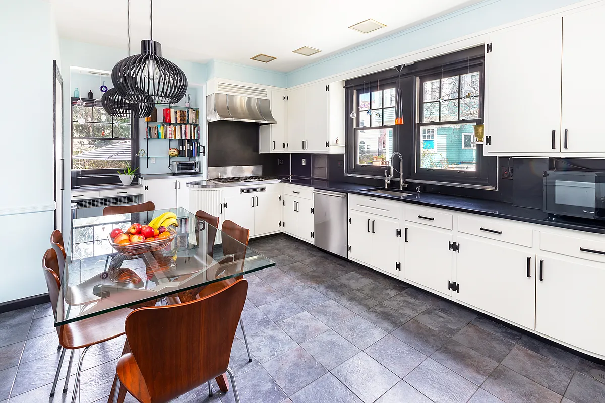 windowed kitchen with white cabinets, gray tile floor