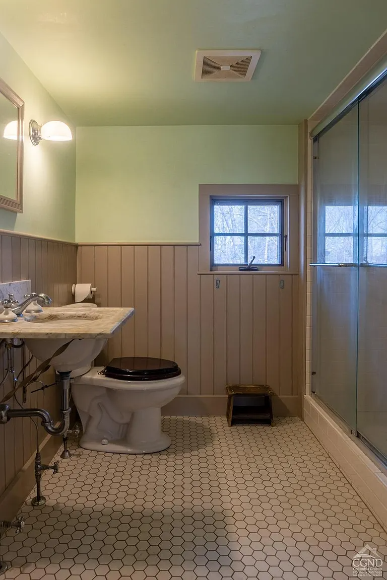 bathroom with hex tile floor, a shower, and a marble sink