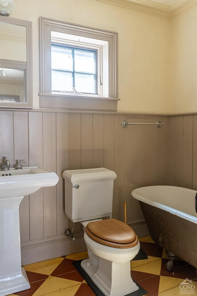 bathroom with wainscoting, white fixtures, a claw foot tub, and a checkerboard painted wood floor