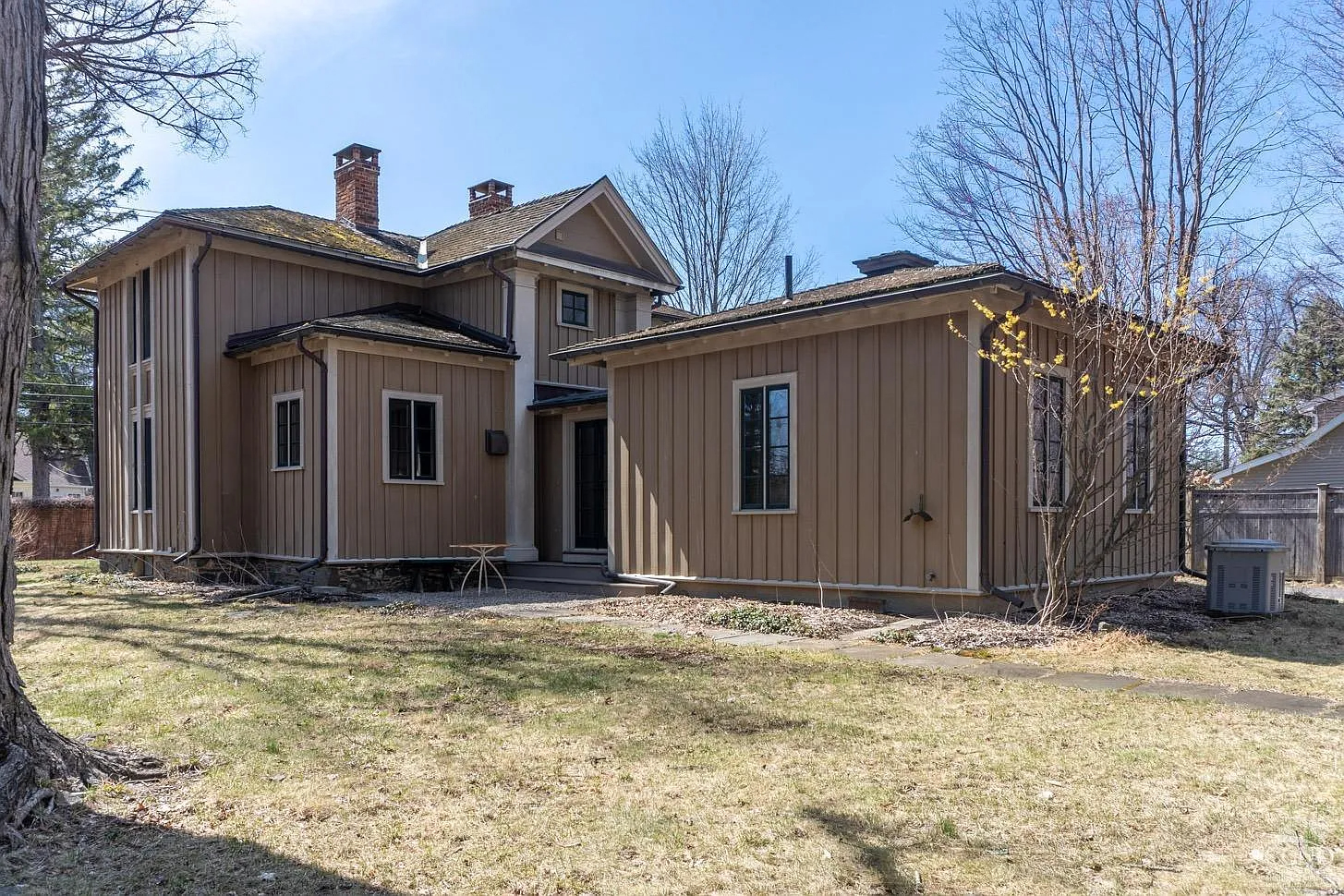 side facade of board and batten cottage showing rear addition