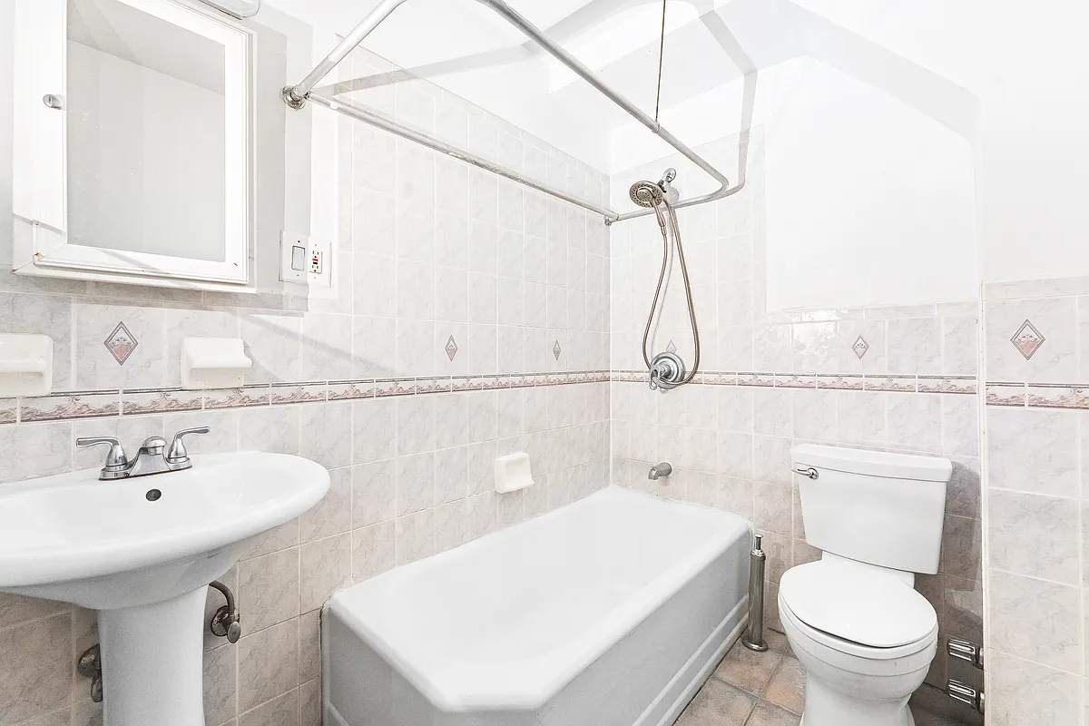 bathroom with beige tile, white fixtures