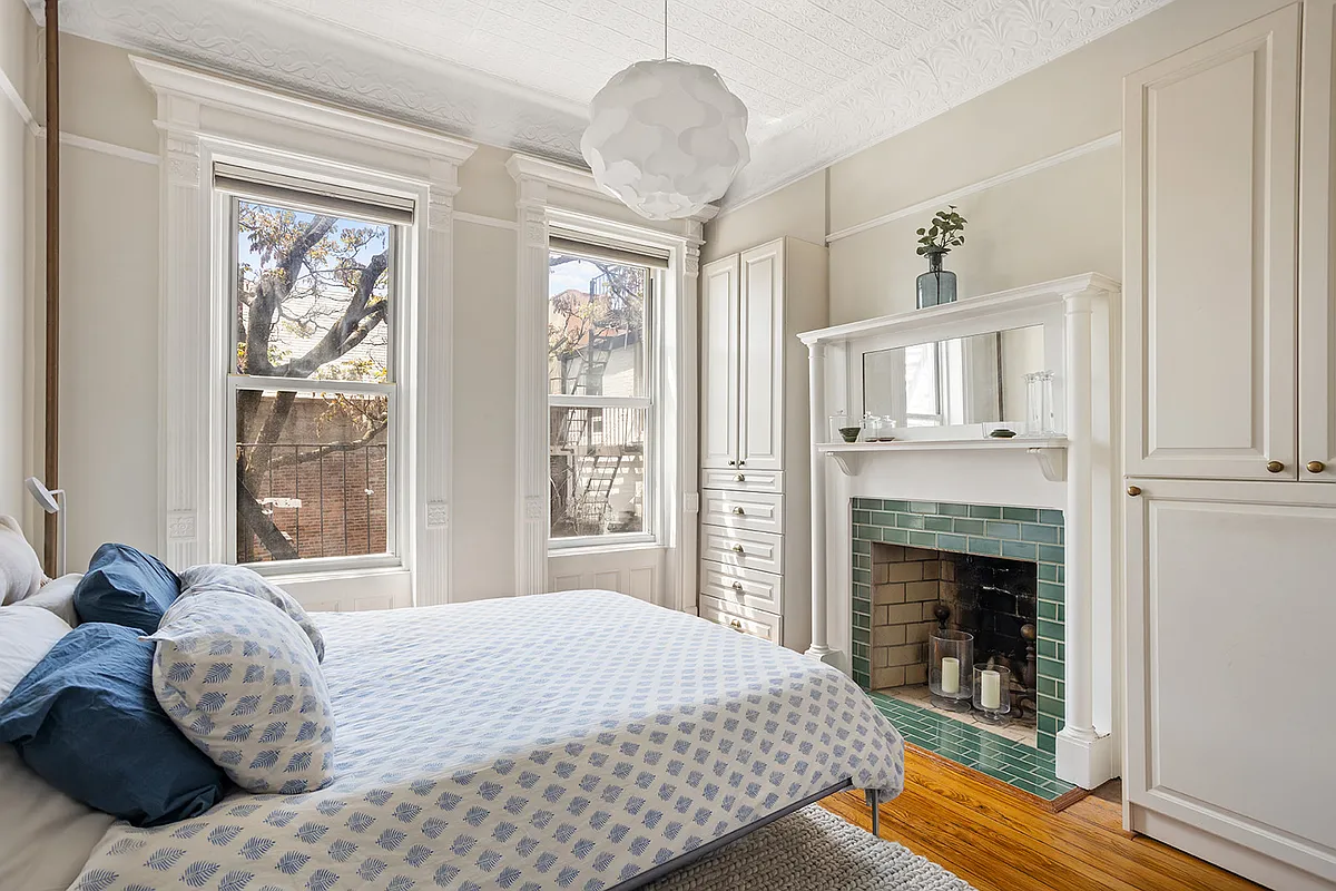 bedroom with mantel, tin ceiling, modern built-ins