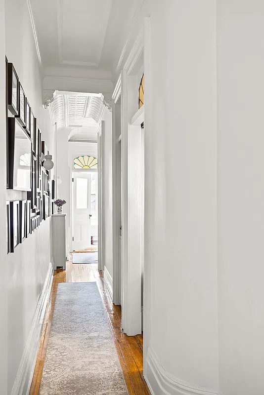 hallway with wood floor, view of stained glass transoms