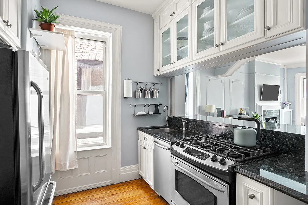 windowed kitchen with white cabinets, stainless steel appliances