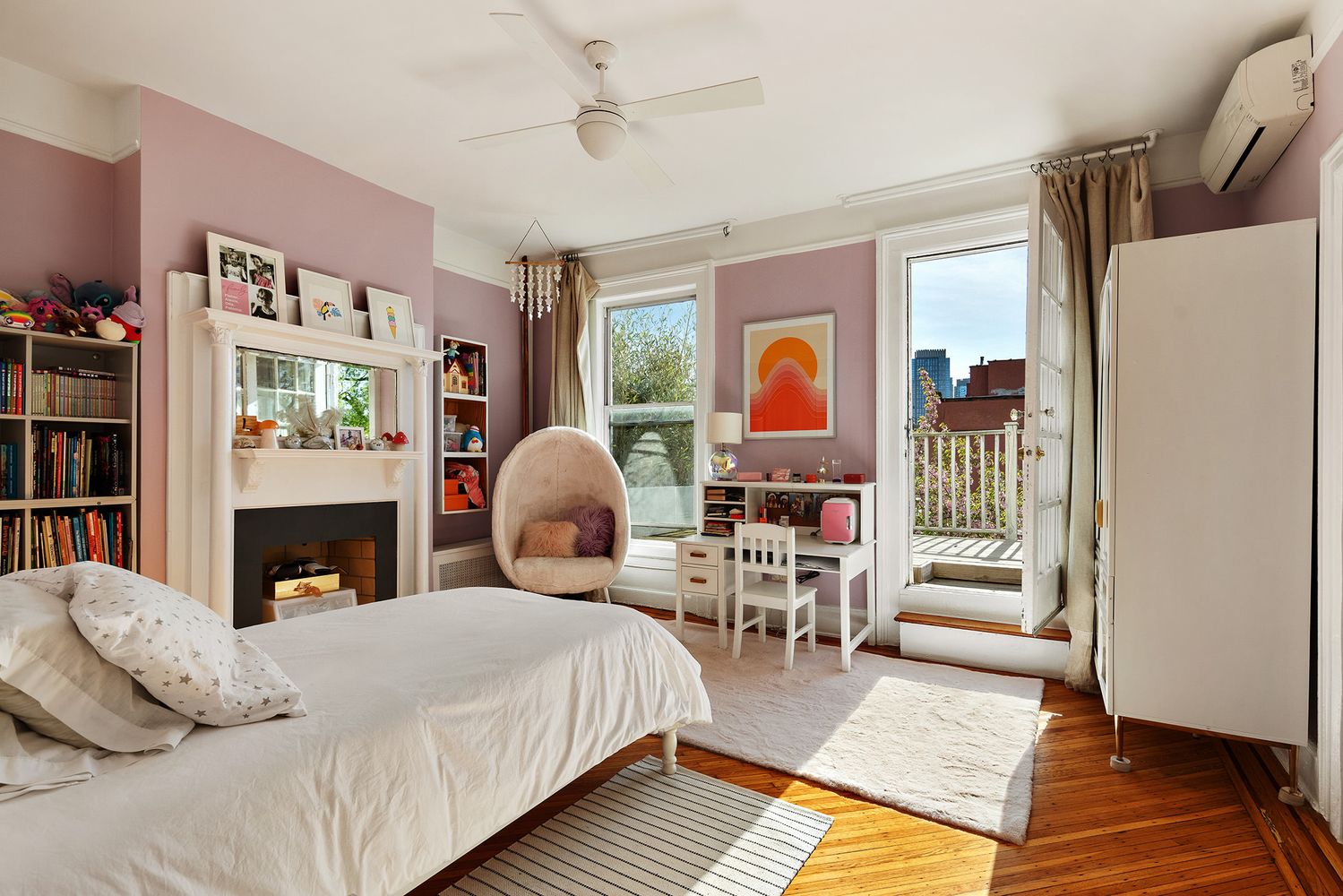 bedroom with pink walls, mantel and a door to a deck