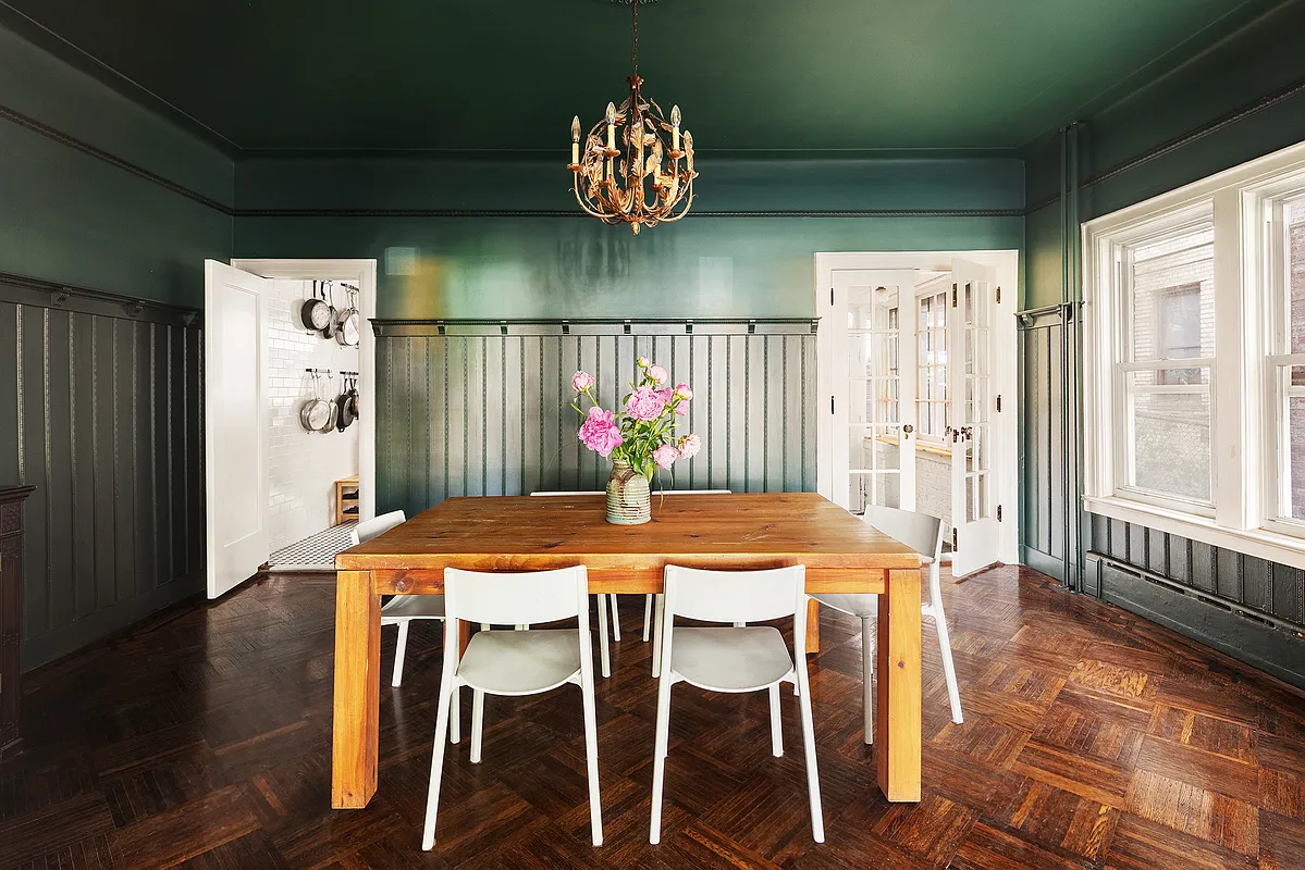dining room with wainscoting, plate shelf and dark green walls
