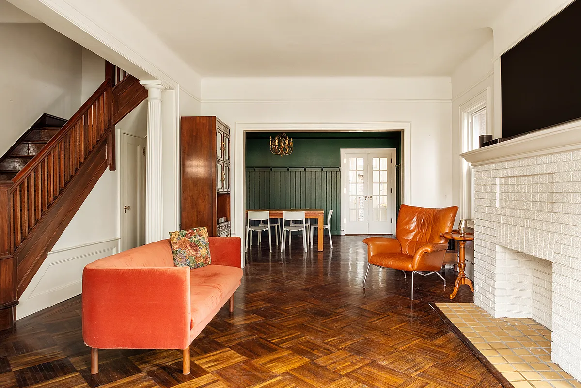 living room with brick mantel, columns, parquet floor and view into dining room