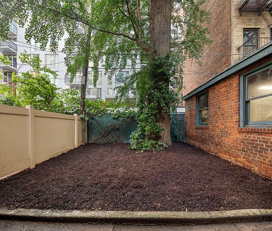 mulched area in the rear yard with a large tree