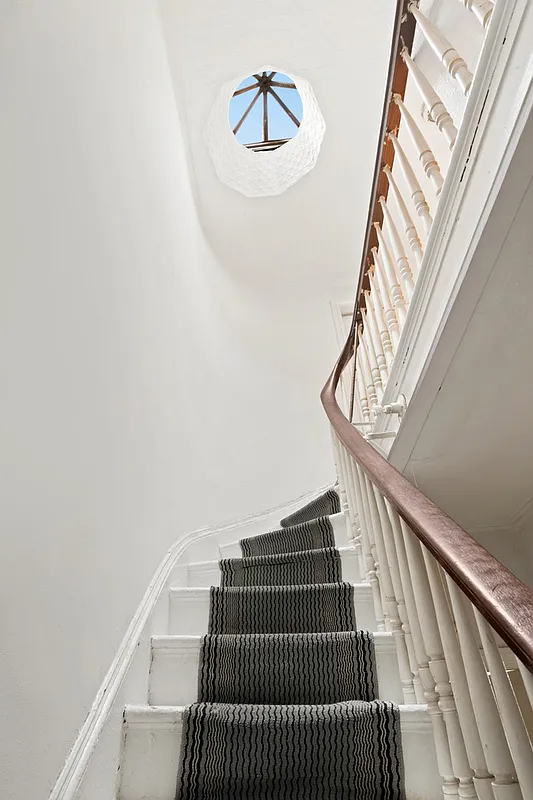 stair with carpet runner and view of a skylight